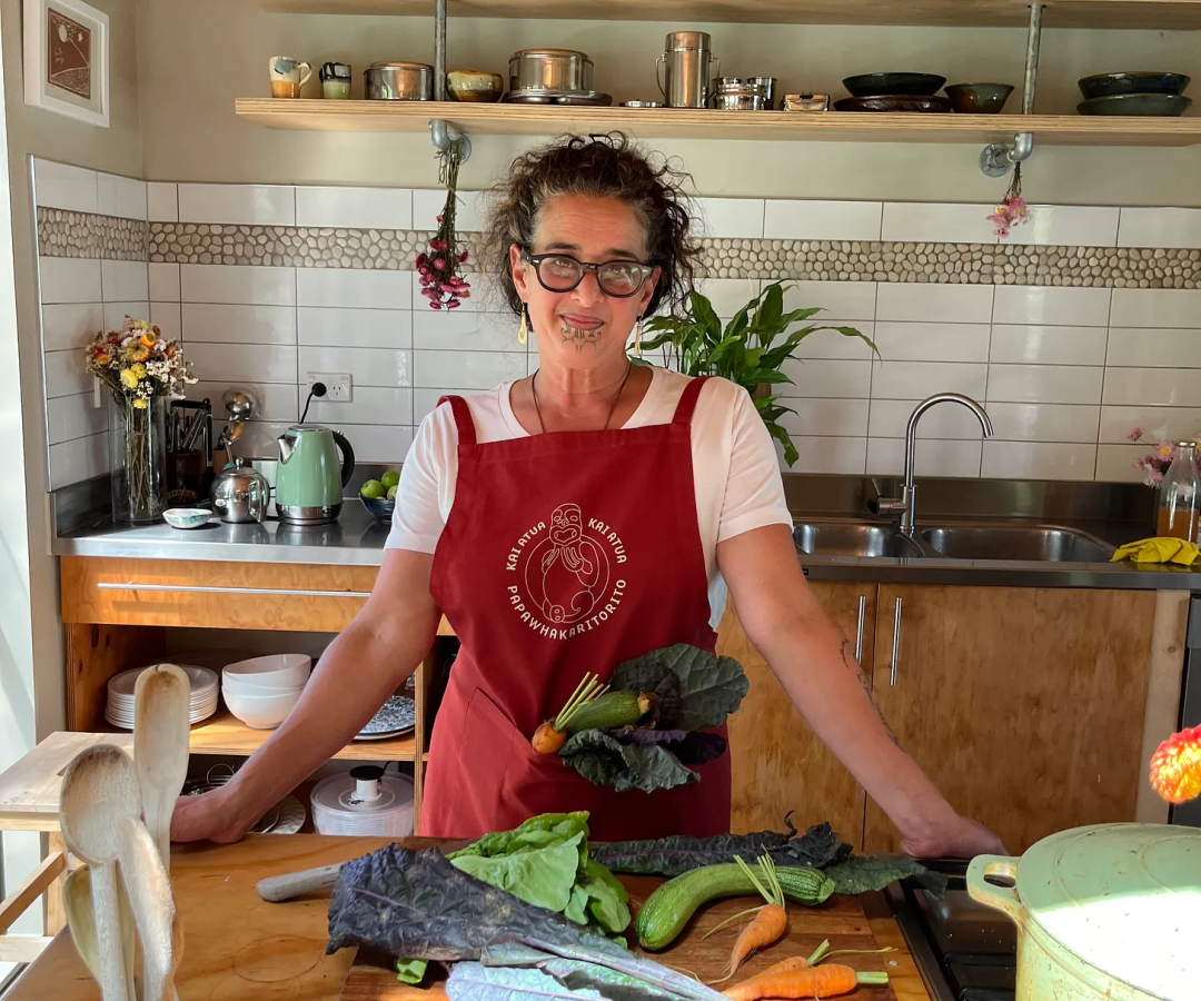 Jessica Hutchings standing in her kitchen wearing a red apron